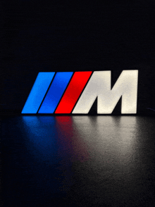 a red white and blue bmw logo that is lit up in the dark