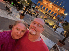 a man and a woman pose for a picture in front of a building