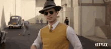 a man wearing a hat and sunglasses is walking down a street in a netflix ad .