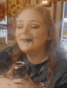 a woman with a spider on her face is drinking a can of coke