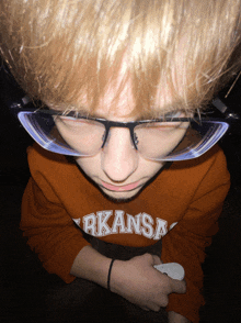 a boy wearing glasses and a sweatshirt that says kansas