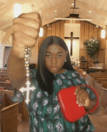 a woman is holding a rosary and a red purse