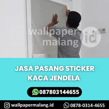 a man is applying a sticker to a window that says wallpaper malang on it