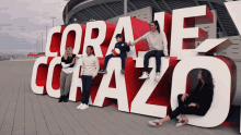 a group of people are posing for a picture in front of a large sign that says " coraje corazon "