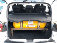 the trunk of a car with a yellow gas tank sitting on top of it .