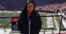 a woman is standing on a balcony overlooking a football stadium .