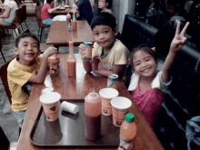 a group of children are sitting at a table with a tray of food and drinks including a can of minute maid orange juice