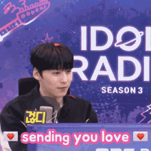 a man in front of a sign that says idol radi season 3