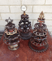 three christmas trees made out of chains and gears are sitting on a table