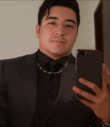 a man in a suit and tie takes a selfie with his phone