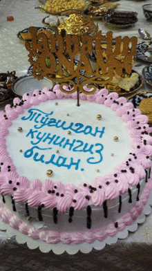 a white cake with pink frosting and a topper that says ' aliyevgan ' on it