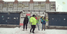 a group of people are dancing in the snow in front of a building with the word my on it