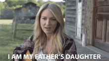 a woman singing while holding a guitar with the words " i am my father 's daughter " behind her