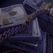 a stack of 100 dollar bills with a gold chain on top