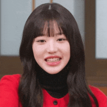 a close up of a woman 's face with a red shirt and black turtleneck