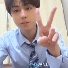 a man in a blue shirt and tie is giving the peace sign