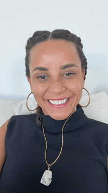 a woman wearing hoop earrings and a necklace smiles