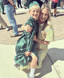 a woman in a green cap and gown holds a young boy in a green cap and gown