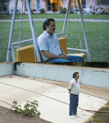 a man is sitting on a swing next to a swimming pool