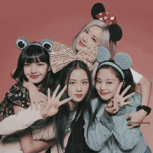 four girls wearing headbands with mickey mouse ears are posing for a photo