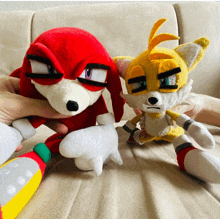 a person is holding a stuffed knuckles and tails toy