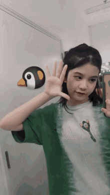 a girl taking a selfie in front of a door with a penguin sticker on it