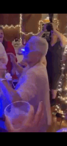 an older woman is dancing at a party while holding a glass .