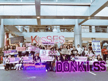 a group of people holding up signs in front of a sign that says kisses