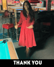 a woman in a red polka dot dress stands in front of a pool table with the words thank you above her