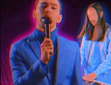 a man in a blue suit is singing into a microphone while another man plays a keyboard in the background .