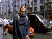 a man in a blue jacket stands in front of a van with a license plate that starts with yv