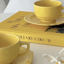 a yellow cup and saucer sitting on top of a yellow book .