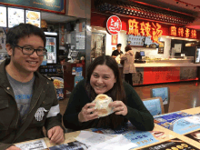 a man and a woman sit at a table in front of a restaurant