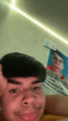 a young man is taking a selfie in front of a wall with a picture of a person on it .