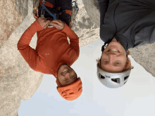 a man wearing a petzl helmet stands next to another man wearing an old sweater