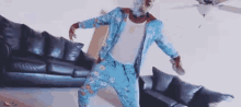 a man in a blue suit is dancing in a living room in front of a couch .