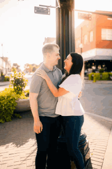 a man and a woman are standing next to each other in front of a street sign that says ' one way '