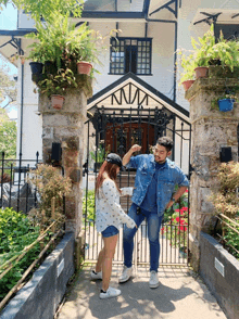 a man and a woman standing in front of a house with the letter n on the front