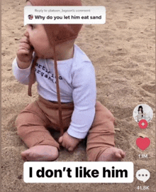 a baby is sitting on the sand with a caption that says " i don 't like him "