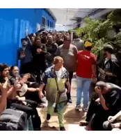 a crowd of people are gathered in front of a blue wall including a man in a red shirt that says pioneer