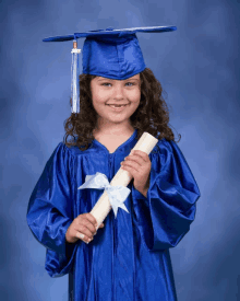 a young girl wearing a graduation cap and gown holds a diploma