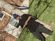 a man in a black shirt and a blue hat stands in front of a brick building