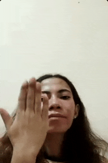 a woman is making a funny face while holding her hand up in front of her face .