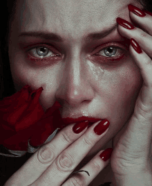 a woman with red nails is crying with a red rose in her mouth