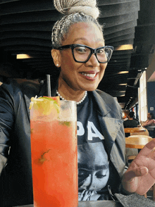 a woman sitting at a table with a drink and a shirt that says pa on it