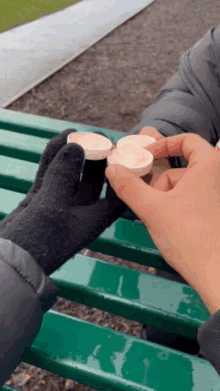 a person wearing black gloves is holding a stack of pills in their hand