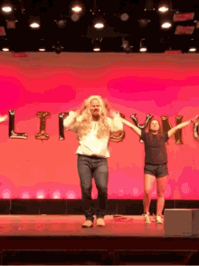 a man in a wig is dancing on a stage in front of a sign that says ' liberty '