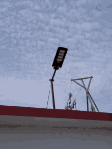 a street light on top of a red roof with a blue sky in the background