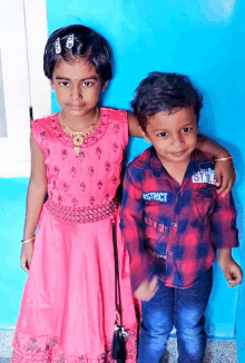 a boy wearing a shirt that says district stands next to a girl in a pink dress