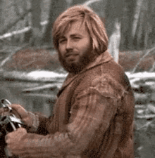 a man with long hair and a beard is riding a motorcycle .